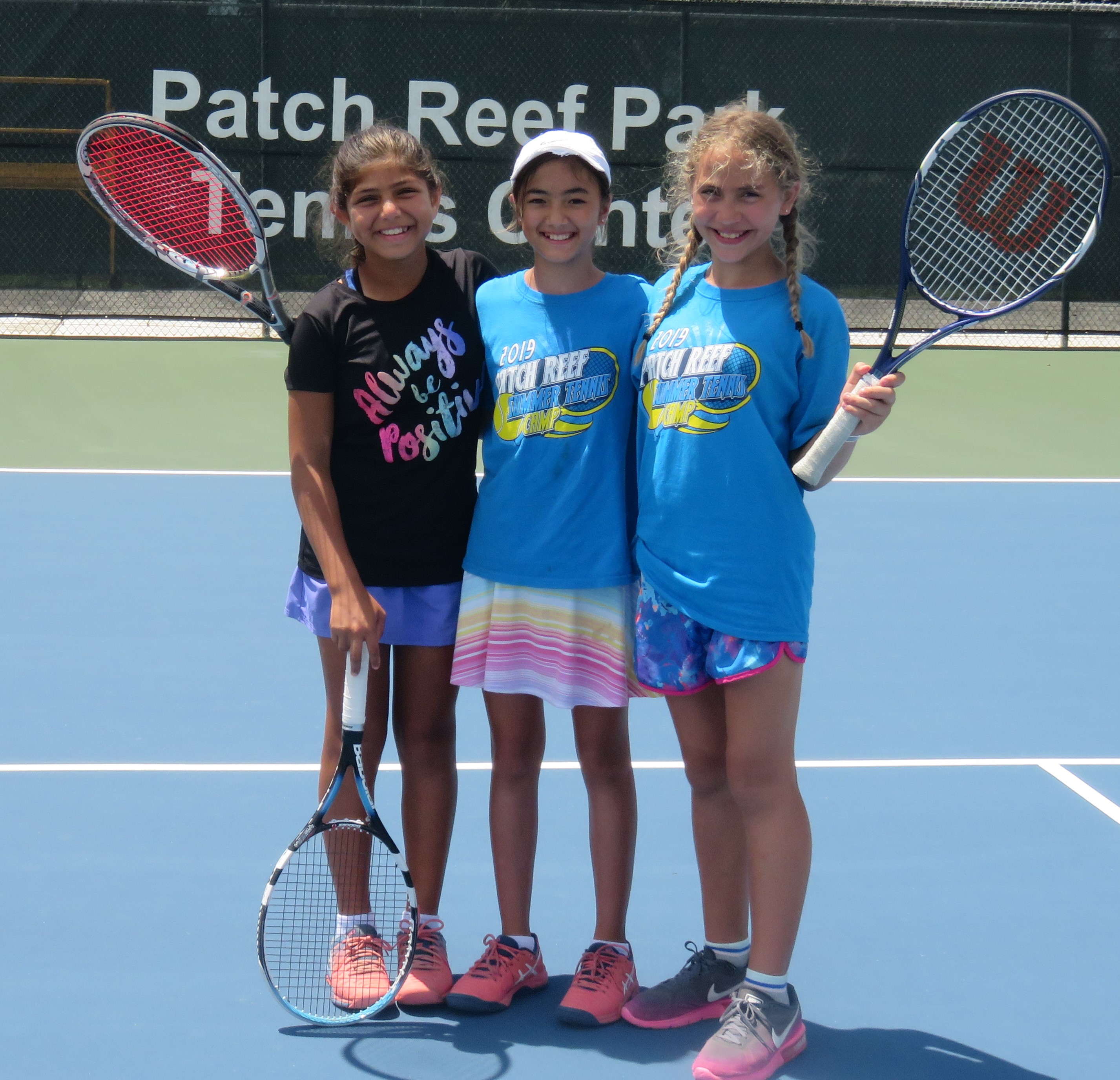 Three girls with tennis racquets smiling